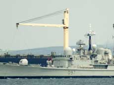 HMS Edinburgh shows off its Sea Dart missile system as it  passes a large bulk carrier